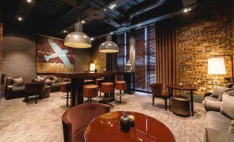 a modern lounge area with wooden tables , chairs , and a bar featuring large hanging lights and an airplane mural at Dakota Eurocentral