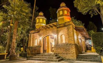a brick building with two domed towers , surrounded by trees and lit up at night at Quinta San Carlos