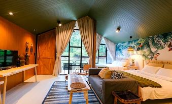 a cozy bedroom with a large bed , a couch , and a tv . also a dining table in the room at Baan Rai Darun Home Stay and Scenery Raft
