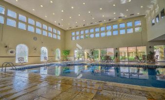 a large indoor swimming pool with multiple windows , surrounded by stone flooring and white walls at Holiday Inn Express Durango