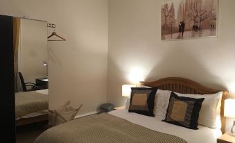 a neatly made bed with a wooden headboard and two pillows is in a room with beige walls at Union Apartments