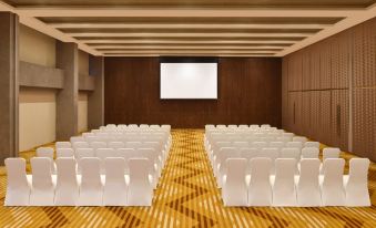 a conference room with rows of white chairs arranged in a semicircle , and a large screen mounted on the wall at Aloft New Delhi Aerocity