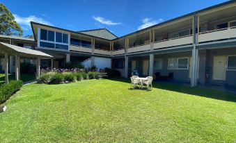 a large , modern building with multiple balconies and a lush green lawn in front of it at Bucketts Way Motel