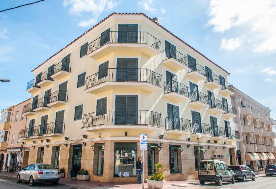 a two - story building with a green awning and balconies is surrounded by cars and trees at Hotel Loar Ferreries