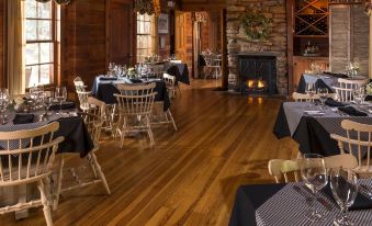 a dining room with wooden floors and tables , chairs , and a fireplace in the background at Glen-Ella Springs Inn