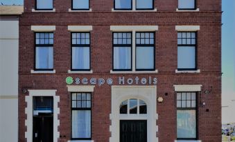 a brick building with multiple windows and doors , possibly a hotel or office building , located on a street corner at Escape Hotel