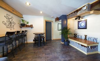 a room with a wooden floor and a large screen tv on the wall , featuring a bar area with tables and chairs at Ski Inn