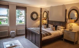 a cozy bedroom with a wooden four - poster bed , a mirror on the wall , and a rug on the floor at Beechfield House