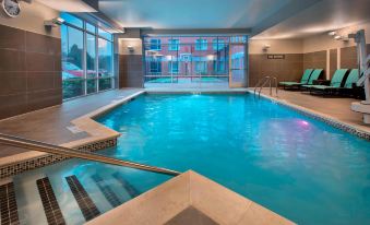 an indoor swimming pool surrounded by glass walls , with a hot tub situated in the middle of the pool at Residence Inn Boston Bridgewater