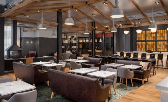 a modern restaurant with wooden tables and chairs , gray booths , and pendant lights hanging from the ceiling at Canopy by Hilton Ithaca Downtown