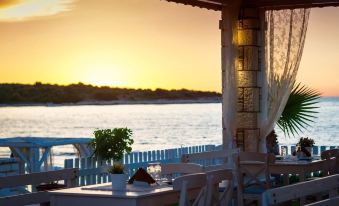 a beautiful sunset view from a dining room on the beach , with chairs and tables set up for diners at Apartment Sofia