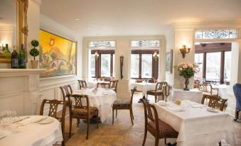 a well - decorated dining room with white tablecloths , chairs , and a painting on the wall , as well as a table setting at Prince of Wales