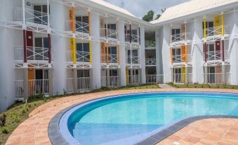 an outdoor swimming pool surrounded by a building , with people enjoying their time in the pool at Hotel Saint - Georges