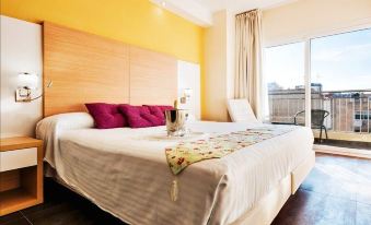 a large bed with white sheets and a red pillow is in a room with yellow walls at Hotel Fontana Plaza
