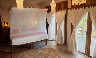 a bedroom with a white mosquito net , wooden furniture , and large windows covered by curtains at Ventana Hotel