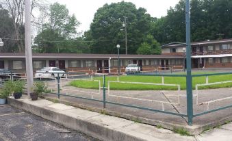 a parking lot with several cars parked in front of a motel , and a few people sitting on the side of the road at H&K Motel