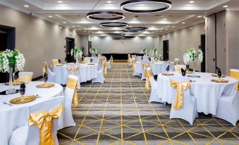 a large , empty banquet hall with white tablecloths and yellow napkins is set up for a formal event at Holiday Inn Statesboro-University Area