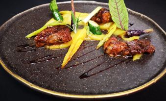 a black plate with two pieces of meat , one on top of the other , sitting on a dining table at Pousada De Viseu