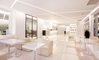 a modern , white - walled lobby with large windows and seating areas , giving it an open and airy feel at Yes Hotel