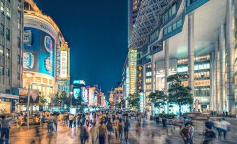 A crowd of people walking down the street at night, passing by buildings at Home Inn Plus (Shanghai Bund Jinling East Road store)