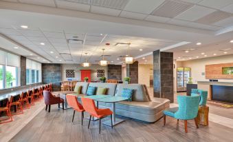 a modern lounge area with multiple couches , chairs , and tables arranged in a spacious room at Home2 Suites by Hilton la Porte