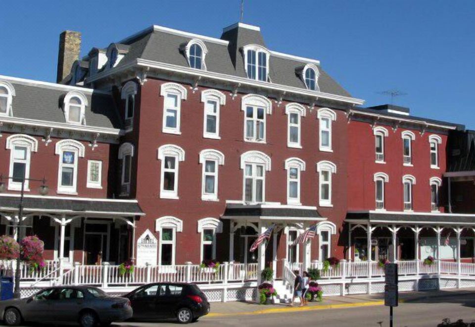 a red brick building with white trim and a black car parked in front of it at Archer House