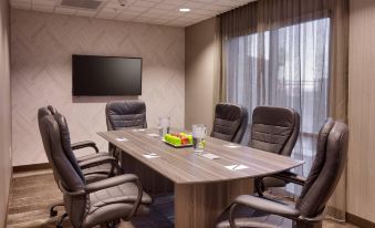 a conference room with a wooden table surrounded by chairs and a tv on the wall at SpringHill Suites Thatcher