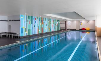 an indoor swimming pool with a blue and white mosaic wall art in the background at Meriton Suites North Ryde