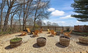 a patio with wooden chairs and a fire pit surrounded by a gravel area , under a blue sky at The Bradford