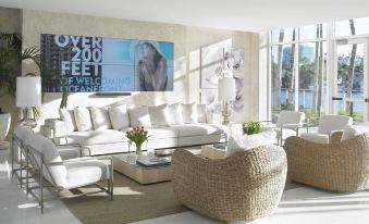 a modern living room with white couches , a wicker chair , and a large poster on the wall at Grand Beach Hotel Bay Harbor