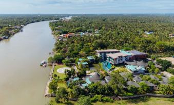 a bird 's eye view of a resort with a large pool , surrounded by trees and water at Na Tree Tara Riverside Resort Amphawa Damnoensaduak