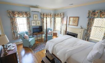 a cozy bedroom with a blue and white color scheme , featuring a bed , chairs , and a tv at The Red Fox Inn & Tavern