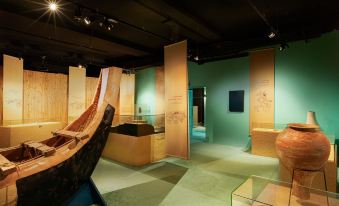 a museum exhibit with various artifacts , including a wooden boat , on display in glass cases at Ras Al Jinz Turtle Reserve