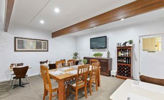 a dining room with a wooden table surrounded by chairs and a television mounted on the wall at Blue Shades Motel