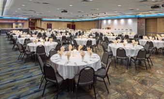 a large banquet hall filled with round tables and chairs , ready for a formal event at Grand Hotel