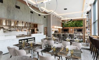 a modern restaurant with marble tables and chairs , pendant lights , and a bar area under hanging lights at AC Hotel Stockholm Ulriksdal