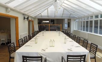 a large dining room with a long table covered in a white tablecloth , surrounded by chairs at The Gower Hotel
