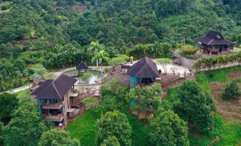 a group of houses nestled in a lush green forest , with a pond in the background at The Waterway Villa