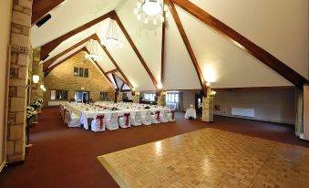 a large room with a wooden floor and multiple tables set up for an event at The Frogmill Hotel
