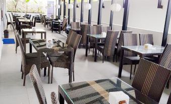 an outdoor dining area with several tables and chairs , some of which are covered with cushions at Bromo Park Hotel Probolinggo