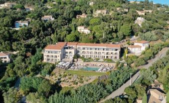 a large , white hotel with multiple buildings and a swimming pool surrounded by trees and other greenery at Hotel la Villa Douce