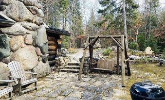 a wooden swing set in a rustic setting , surrounded by trees and a stone building at Drummond Island Resort & Conference Center