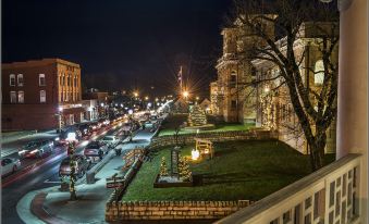 a bustling city street at night , with numerous cars and people on the sidewalk , and a large building illuminated by street lights at The Inn at Wise