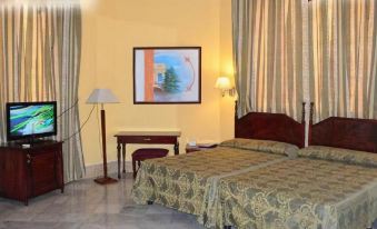 a well - decorated hotel room with two beds , curtains , and a tv , giving it a cozy and inviting atmosphere at Hostal la Casona