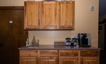 a kitchen with wooden cabinets and a granite countertop , featuring a sink , coffee maker , and coffee pot at The Old Lantern Inn and Barn