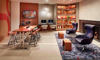 a modern office space with various furniture , including chairs , desks , and bookshelves , arranged in a comfortable open space at San Mateo Marriott San Francisco Airport