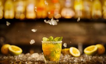 a cocktail with a lemon slice and mint leaves is being served on a bed of ice at The Fortress Resort & Spa