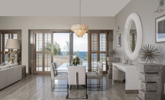 a modern dining room with a large table , chairs , and a chandelier hanging from the ceiling at Four Seasons Resort and Residence Anguilla