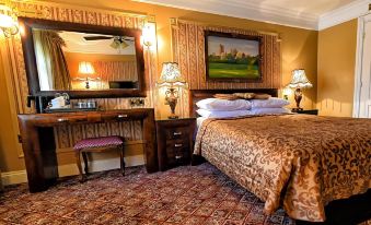 a large bed with a leopard print comforter is in the center of a room with a desk , chair , and lamp at Riverside Inn