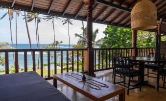 a wooden deck overlooking the ocean , with a dining table and chairs set up for a meal at Eraeliya Villas & Gardens